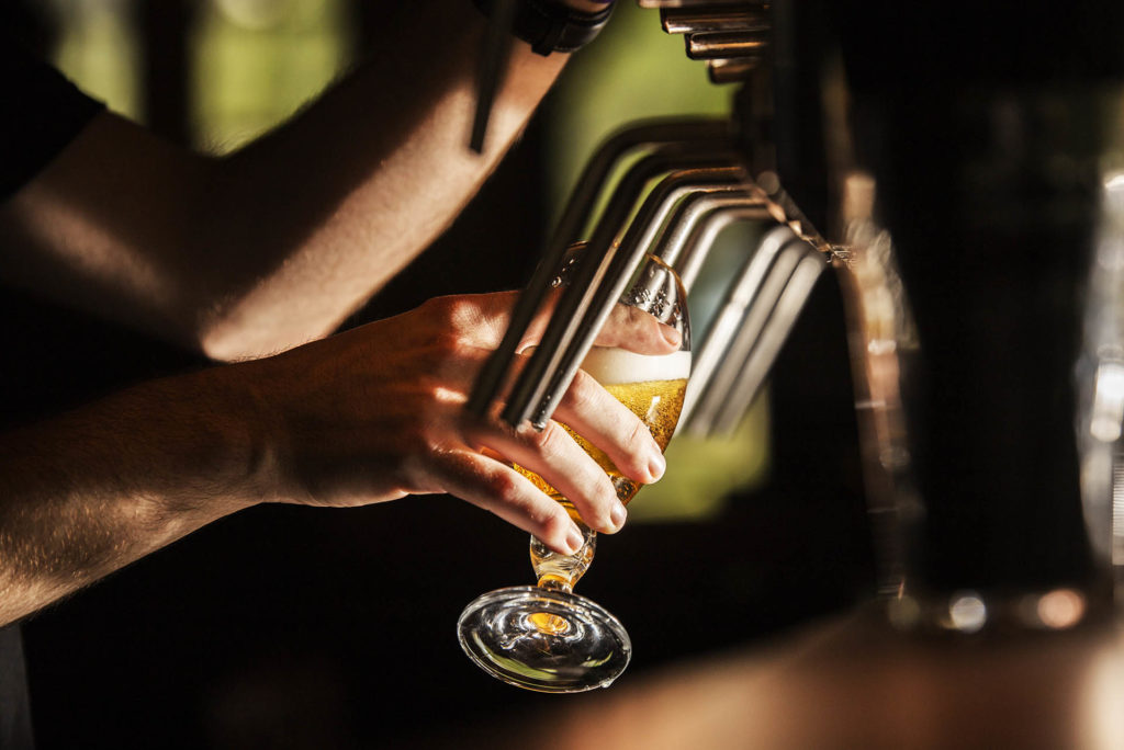 Barman dans un bar avec un verre de bière